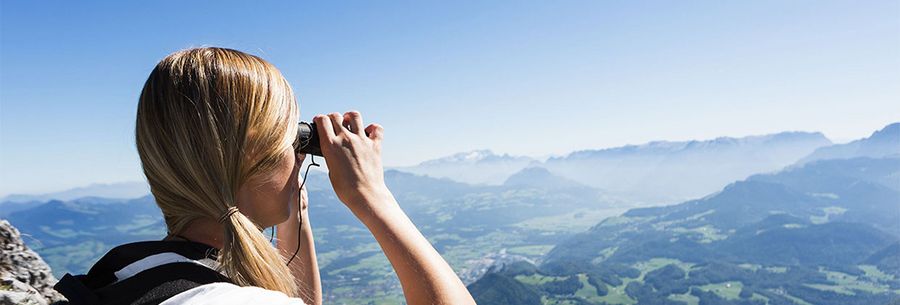 Frau blickt mit Fernglas in die Ferne Frau blickt mit Fernglas in die Ferne